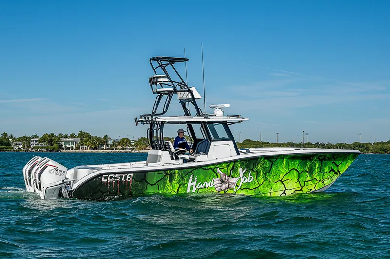 Slide: The Image of 2024 Costa Custom Boats 34 cruising on water, surrounded by lush greenery. - 49