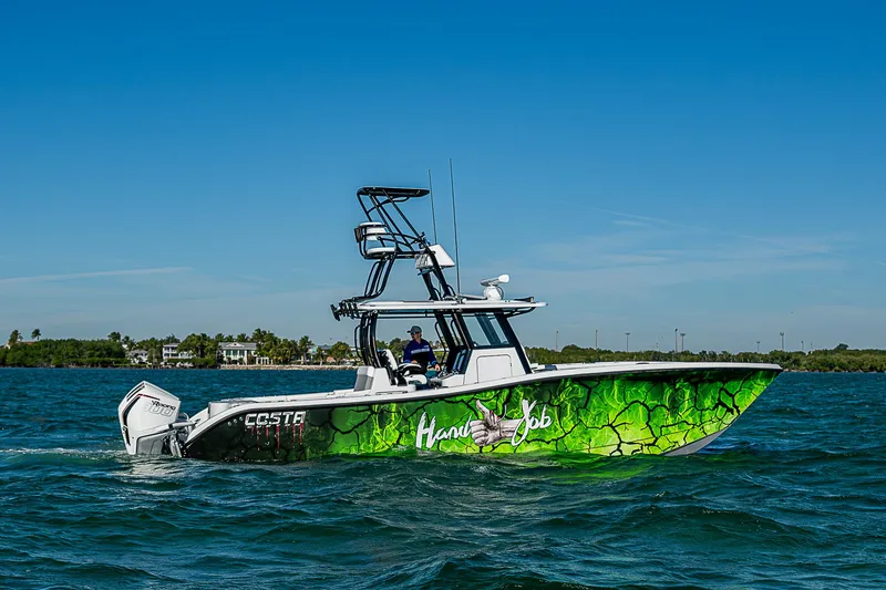Slide: The Image of 2024 Costa Custom Boats 34 cruising on a scenic waterway with lush greenery. - 50