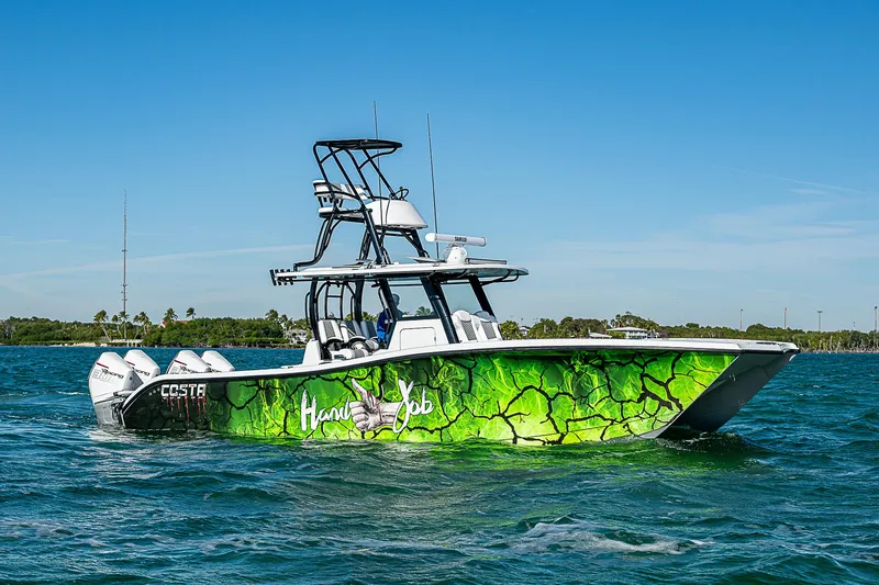 Slide: The Image of 2024 Costa Custom Boats 34 cruising on a scenic waterway with lush greenery. - 51