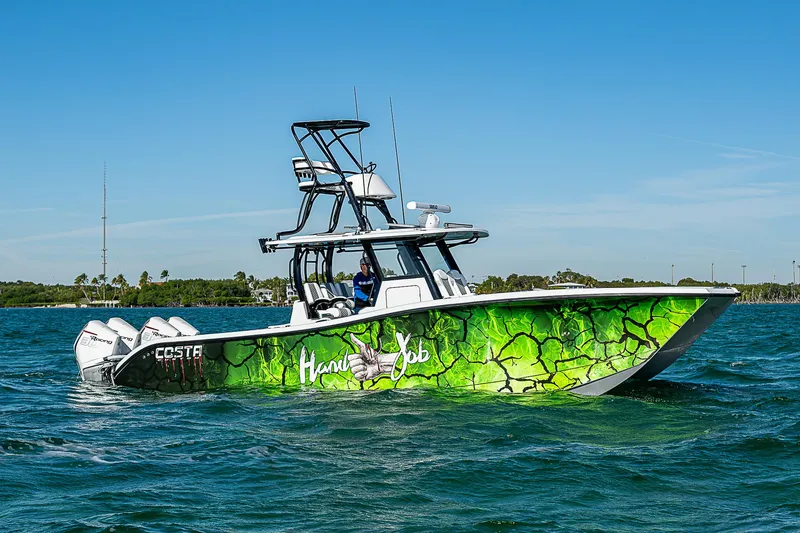 Slide: The Image of 2024 Costa Custom Boats 34 cruising on a scenic waterway with lush greenery. - 52