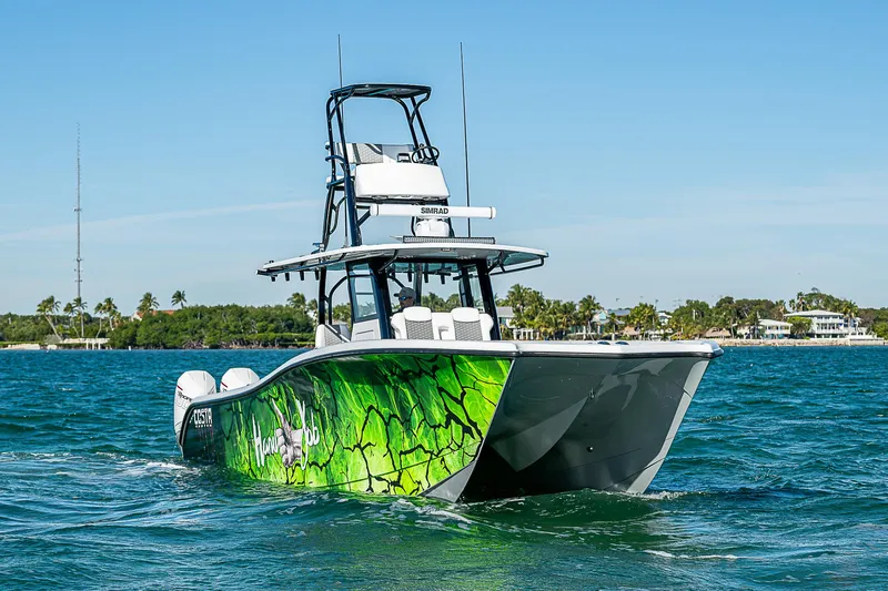 Slide: The Image of 2024 Costa Custom Boats 34 cruising on a scenic waterway with lush greenery. - 53