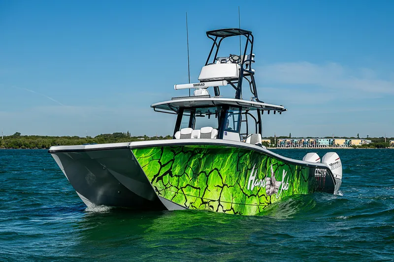 Slide: The Image of 2024 Costa Custom Boats 34 cruising on a scenic waterway with lush greenery. - 56