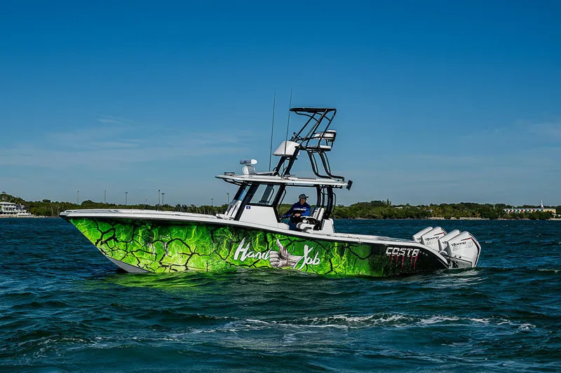 Slide: The Image of 2024 Costa Custom Boats 34 cruising on a scenic waterway with lush greenery. - 60