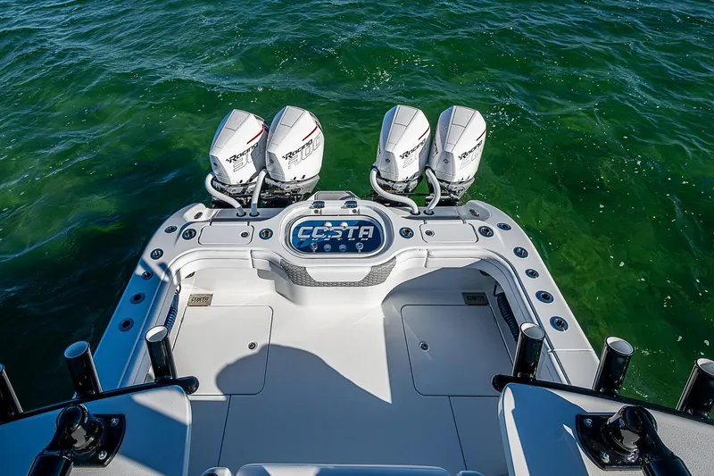 Slide: The Image of 2024 Costa Custom Boats 34 cruising on a scenic waterway under a clear blue sky. - 61