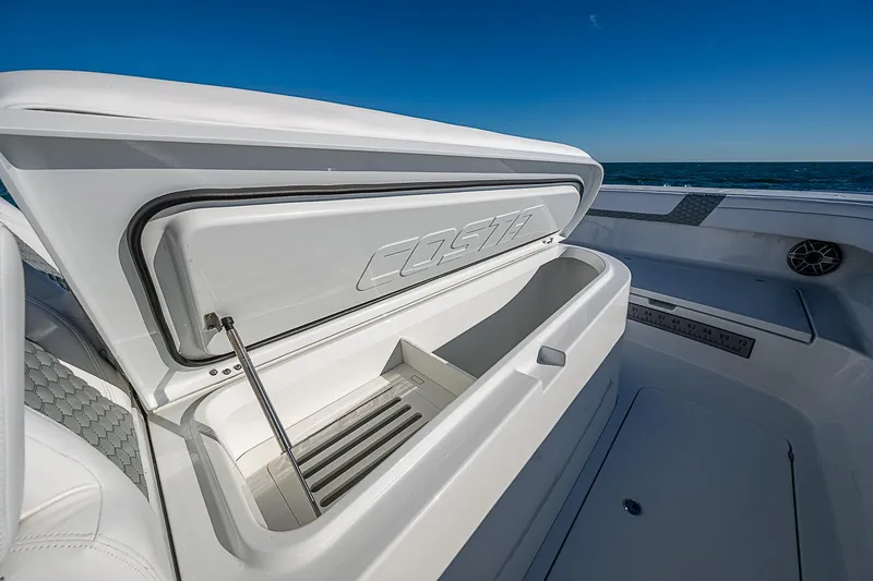 Slide: The Image of 2024 Costa Custom Boats 34 cruising on water, surrounded by lush greenery. - 98