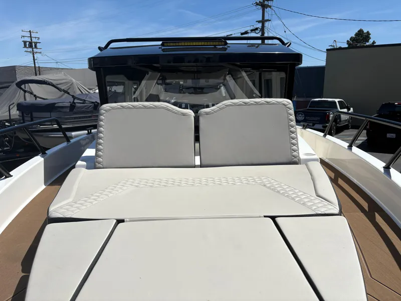 Slide: The Image of 2025 Navan C30 boat with white cushioned seating, docked under clear blue sky. - 14