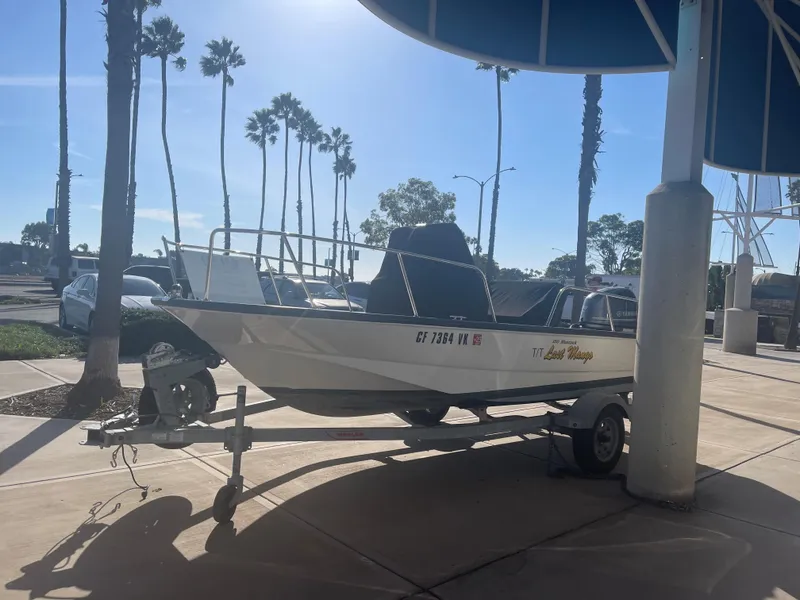 Slide: The Image of 2017 Boston Whaler 150 Montauk boat on trailer, parked under palm trees. - 9
