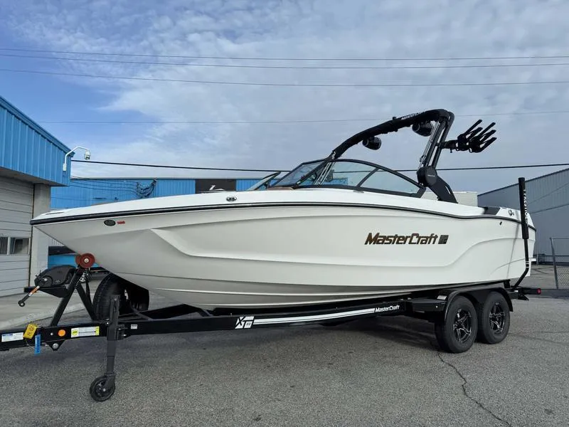 Slide: The Image of 2025 MasterCraft XT23 boat on trailer, parked outside a blue building. - 3