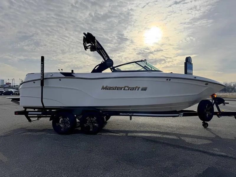 Slide: The Image of 2025 MasterCraft XT23 boat on trailer under cloudy sky. - 5