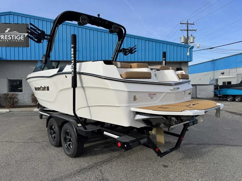 Slide: The Image of 2025 MasterCraft XT23 boat on trailer, parked outside a blue building. - 7