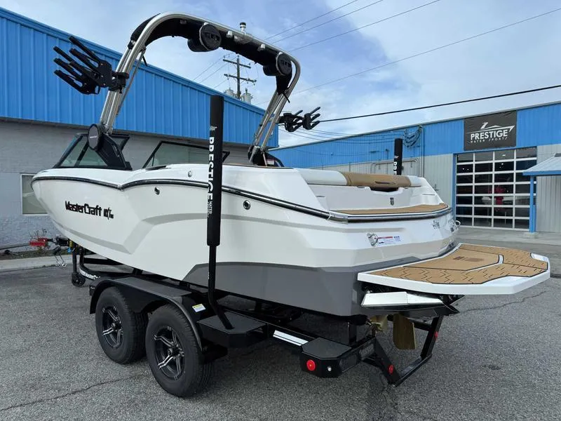 Slide: The Image of 2025 MasterCraft NXT20 boat on trailer, parked outside a blue building. - 6