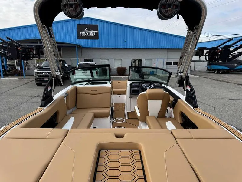 Slide: The Image of 2025 MasterCraft NXT20 boat interior with tan seating, parked at a dealership. - 7