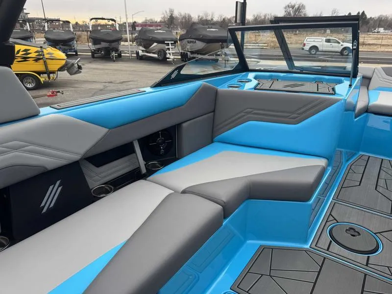 Slide: The Image of 2025 ATX Surf Boats 22 Type-S interior with blue and gray seating, docked with other boats. - 10