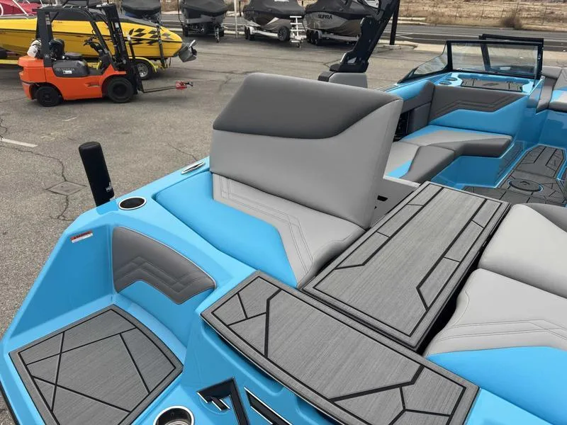 Slide: The Image of 2025 ATX Surf Boats 22 Type-S interior with blue and gray seating, docked near other boats. - 3