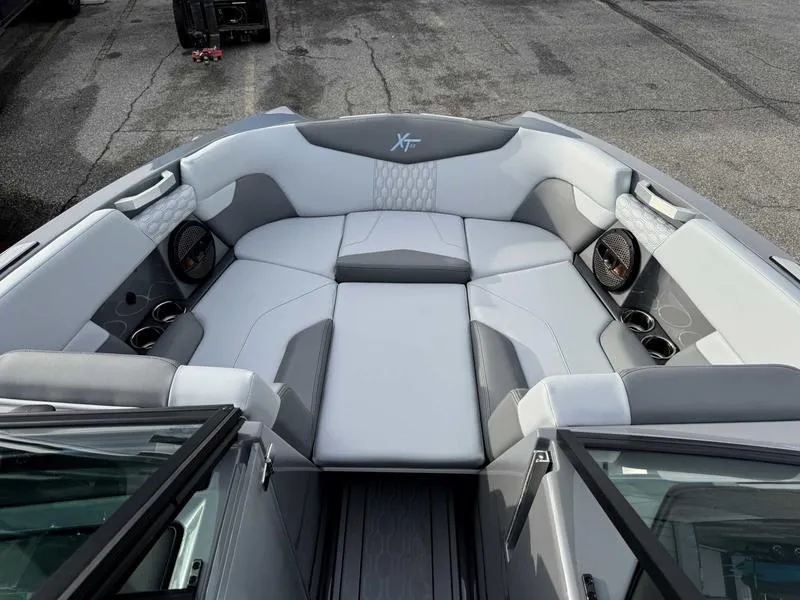 Slide: The Image of 2025 MasterCraft XT22 boat interior with gray and white seating, cup holders, and speakers. - 13
