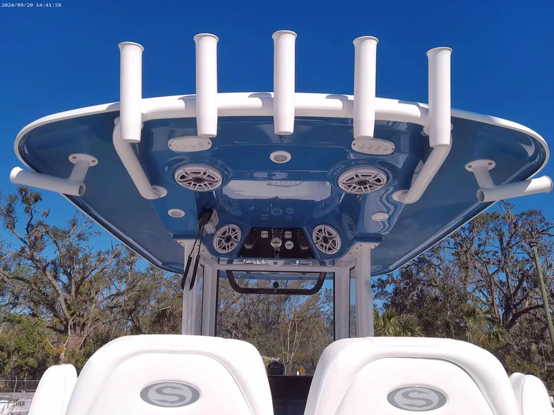 Slide: The Image of 2025 Sportsman Masters 267OE Bay Boat with rod holders and speakers under blue sky. - 6