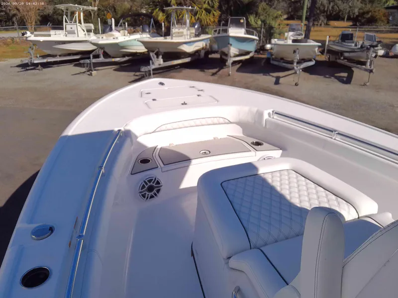 Slide: The Image of 2025 Sportsman Masters 267OE Bay Boat with white seating and deck, parked among other boats. - 8