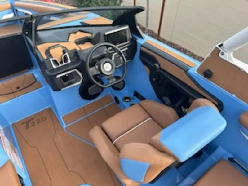 Slide: The Image of 2025 Axis T220 boat interior with blue and tan seating, modern dashboard, and steering wheel. - 13