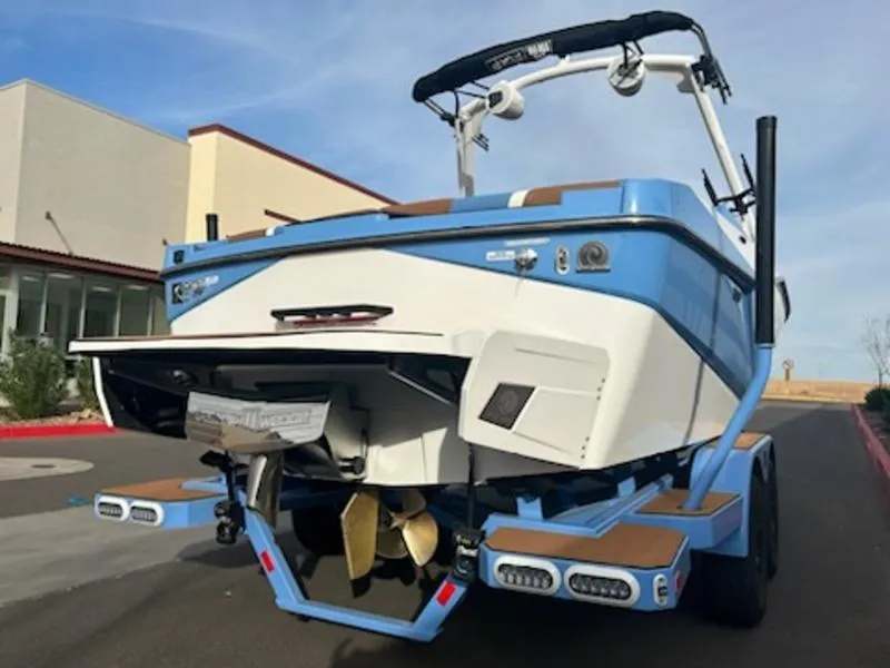 Slide: The Image of 2025 Axis T220 boat, blue and white, parked on a trailer. - 5