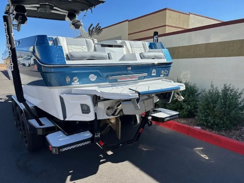 Slide: The Image of 2025 Malibu 26 LSV boat, blue and white, parked outdoors on a sunny day. - 4