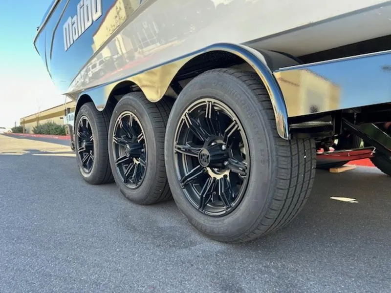 Slide: The Image of 2025 Malibu 26 LSV boat trailer with sleek black wheels on pavement. - 6