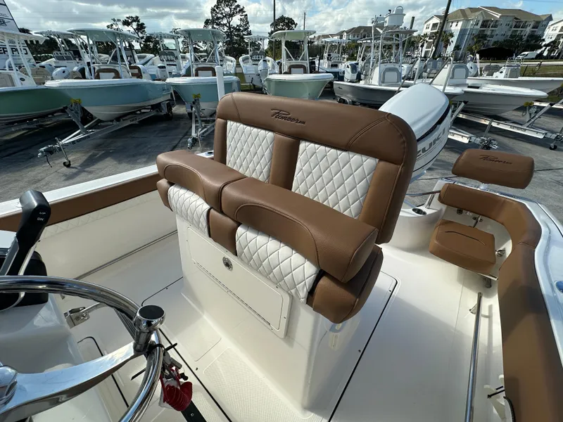 Slide: The Image of 2025 Pioneer 222 Sportfish boat with brown and white seating, docked among other boats. - 11