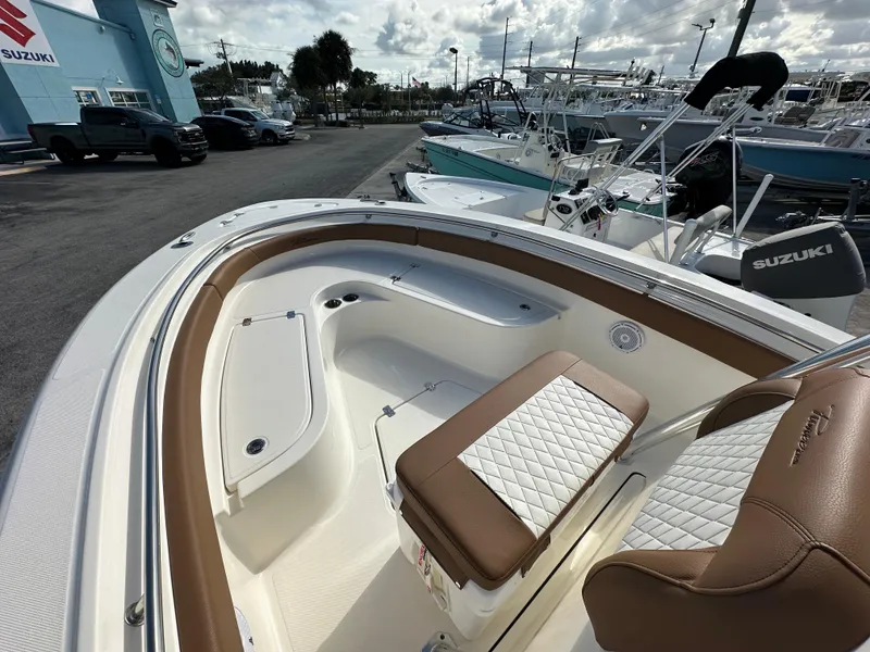 Slide: The Image of 2025 Pioneer 222 Sportfish boat interior with brown and white seating, docked at a marina. - 6