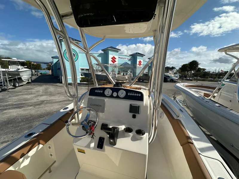 Slide: The Image of 2025 Pioneer 202 Sportfish boat interior with steering console and gauges, parked outdoors. - 5