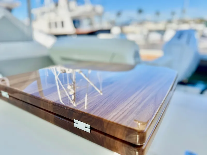 Slide: The Image of Polished wood detail on 2025 Tiara Yachts 34 LX, with blurred marina background. - 20