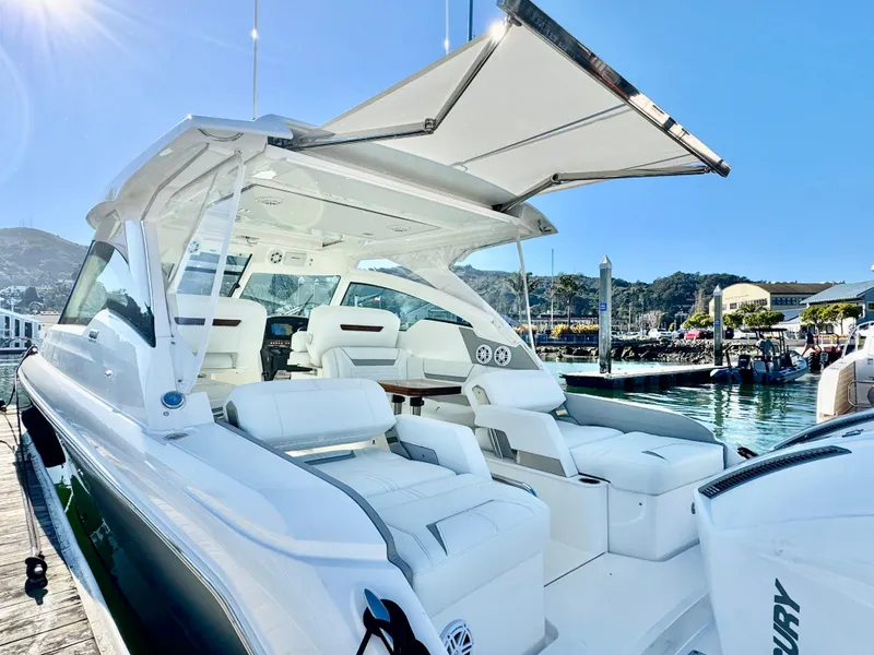 Slide: The Image of 2025 Tiara Yachts 34 LX luxury boat with spacious seating and sunshade at marina. - 24