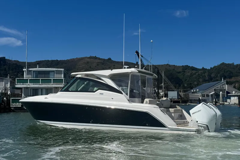 Slide: The Image of 2026 Tiara Yachts 34 LX cruising in a marina with scenic background. - 6