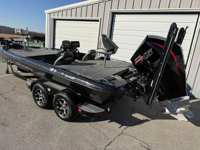 Slide: The Image of 2022 Phoenix 721 Pro XP bass boat with powerful engine, parked outside a garage. - 2
