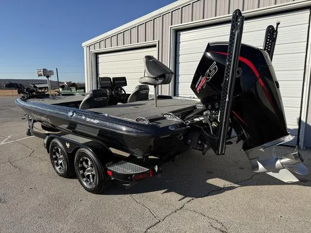 Slide: The Image of 2022 Phoenix 721 Pro XP bass boat with powerful outboard motor, parked outside a garage. - 3