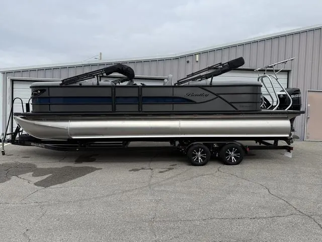 Slide: The Image of 2025 Bentley Pontoons Legacy 243 Navigator on trailer, parked outside a warehouse. - 1