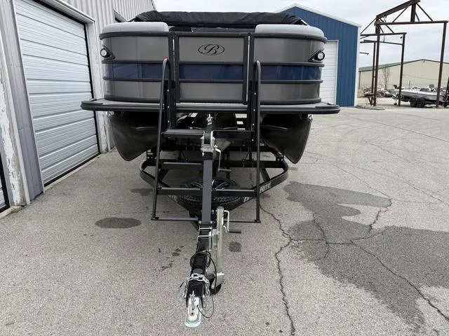 Slide: The Image of 2025 Bentley Pontoons Legacy 243 Navigator on trailer, parked near industrial buildings. - 6