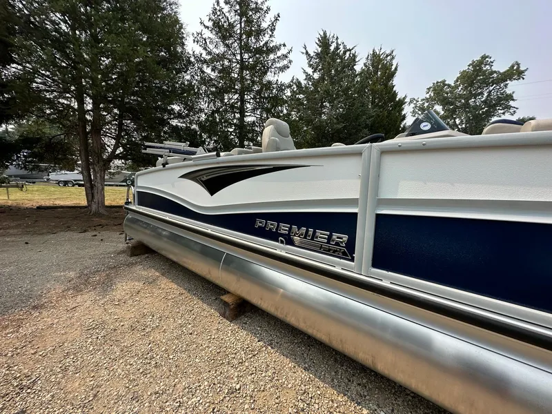 Slide: The Image of 2023 Premier 250 Solaris RF pontoon boat parked on gravel near trees. - 0