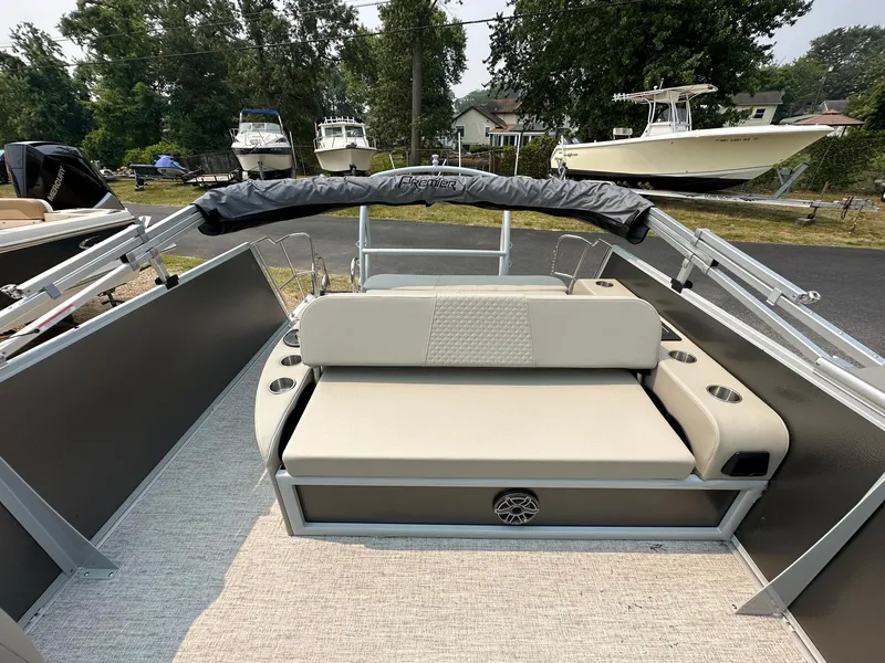 Slide: The Image of 2023 Premier 250 Solaris RL boat with beige seating and cup holders, docked outdoors. - 11