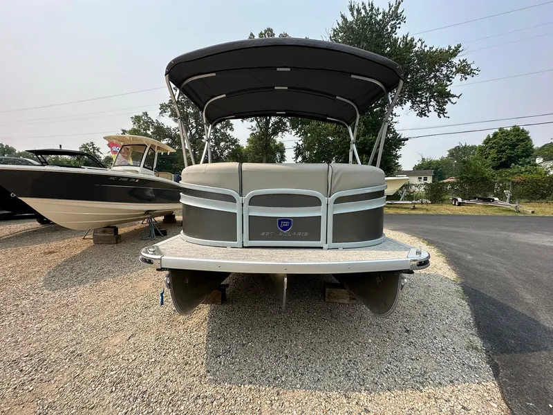 Slide: The Image of 2023 Premier 250 Solaris RL pontoon boat with canopy, parked on gravel. - 3