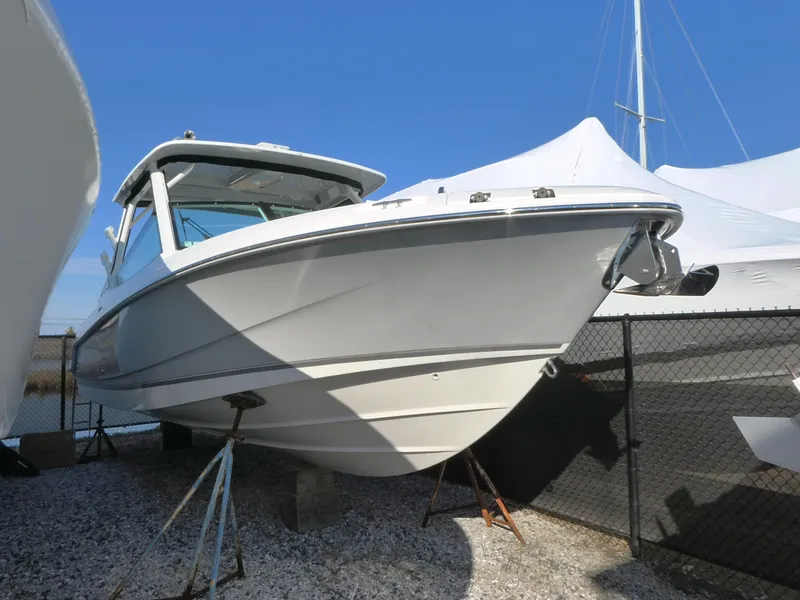The Image of 2025 Boston Whaler 280 Vantage boat on display, elevated on stands, with a clear blue sky. - 0