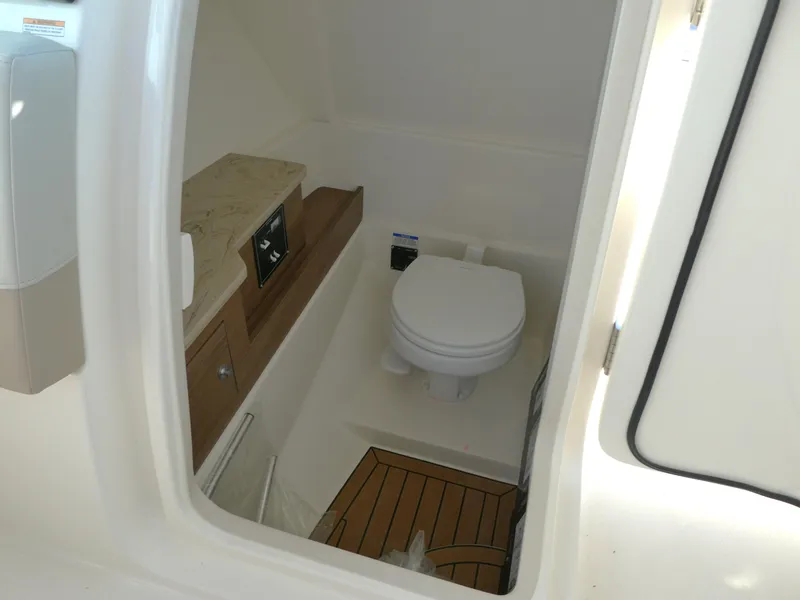 Slide: The Image of Interior of 2025 Boston Whaler 280 Vantage boat, featuring a compact marine toilet. - 16
