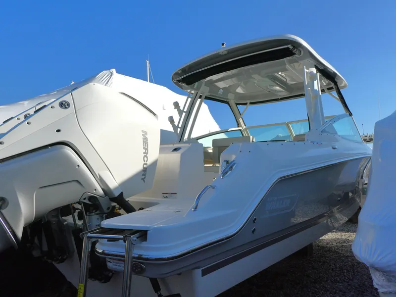 Slide: The Image of 2025 Boston Whaler 280 Vantage boat with Mercury outboard engine, docked under clear blue sky. - 2