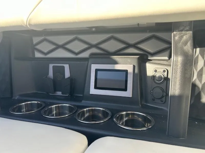 Slide: The Image of 2025 Malibu M230 boat interior with touchscreen, cup holders, and phone holder. - 21