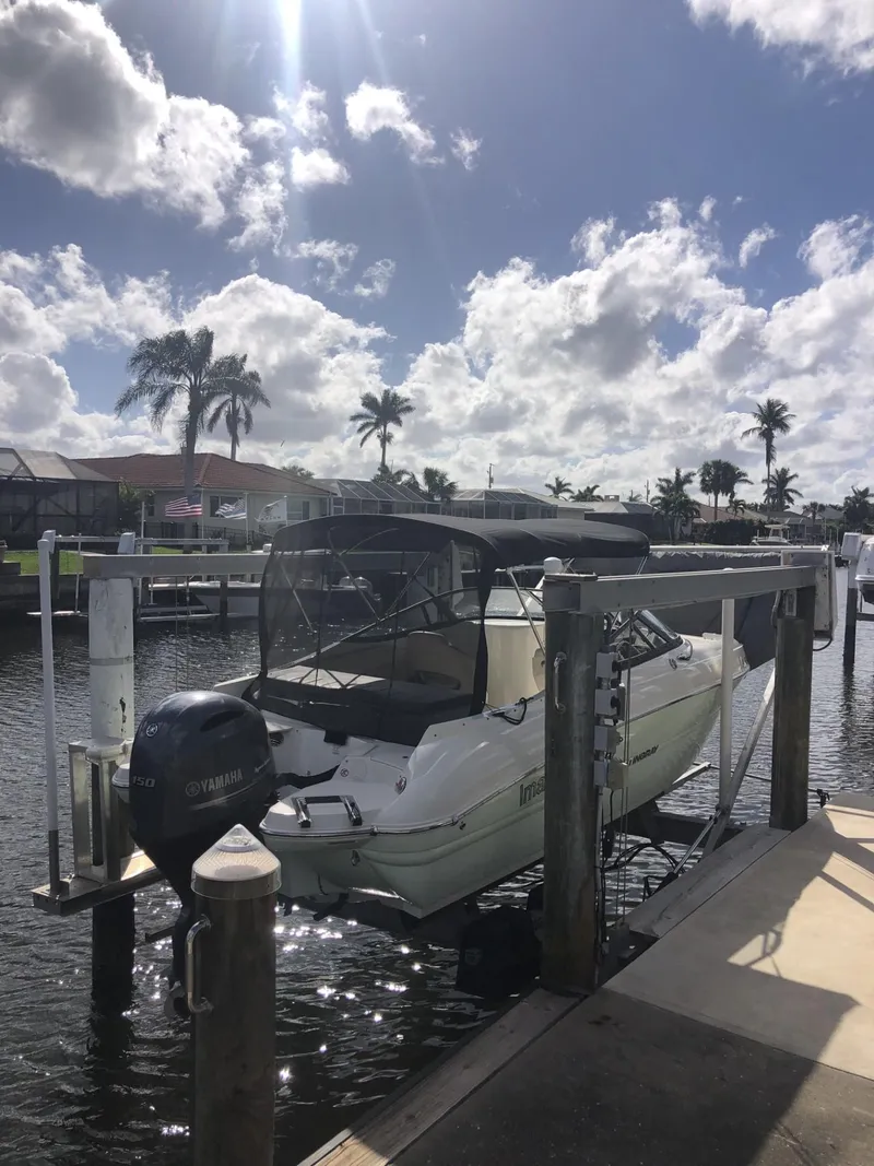 Slide: The Image of 2021 Stingray 214 LR boat docked under a sunny sky with palm trees. - 10