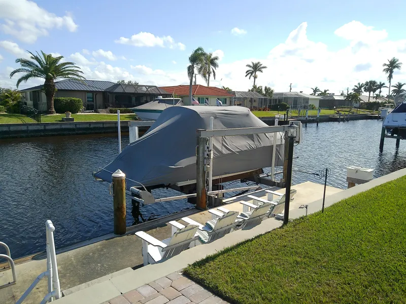 Slide: The Image of Covered 2021 Stingray 214 LR boat docked by a canal with palm trees. - 3