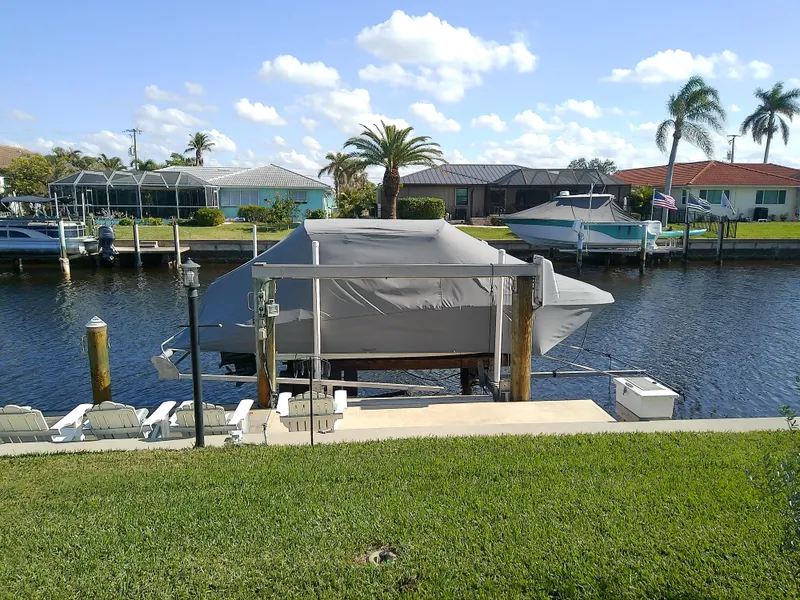 Slide: The Image of Covered 2021 Stingray 214 LR boat docked by a canal with palm trees. - 4