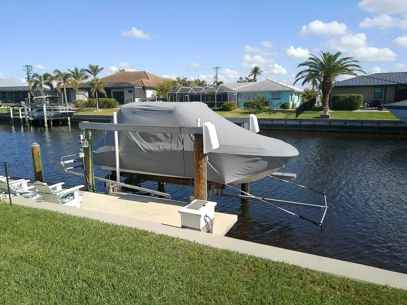 Slide: The Image of Covered 2021 Stingray 214 LR boat on lift by canal, sunny day. - 5