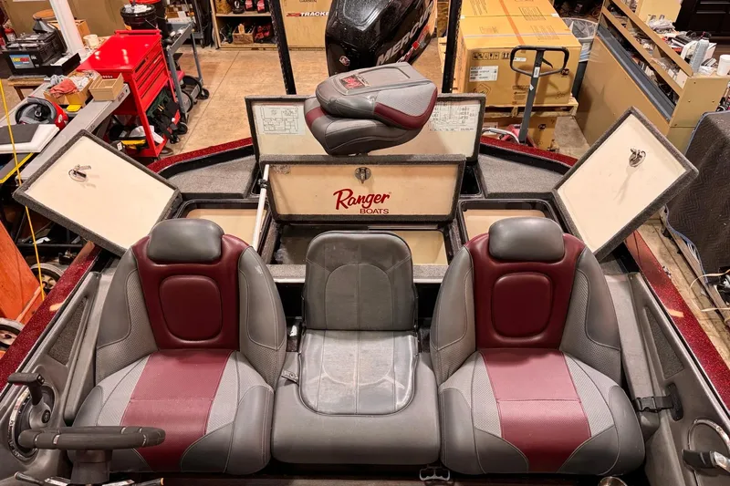 Slide: The Image of 2017 Ranger Z520 Comanche boat interior with red and gray seats in a workshop setting. - 5
