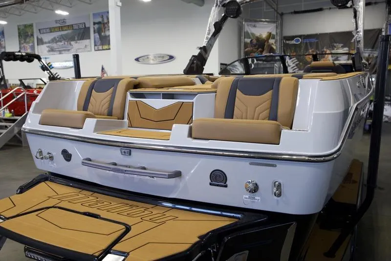 Slide: The Image of 2025 Malibu 25 LSV boat interior with tan and black seating in showroom. - 10