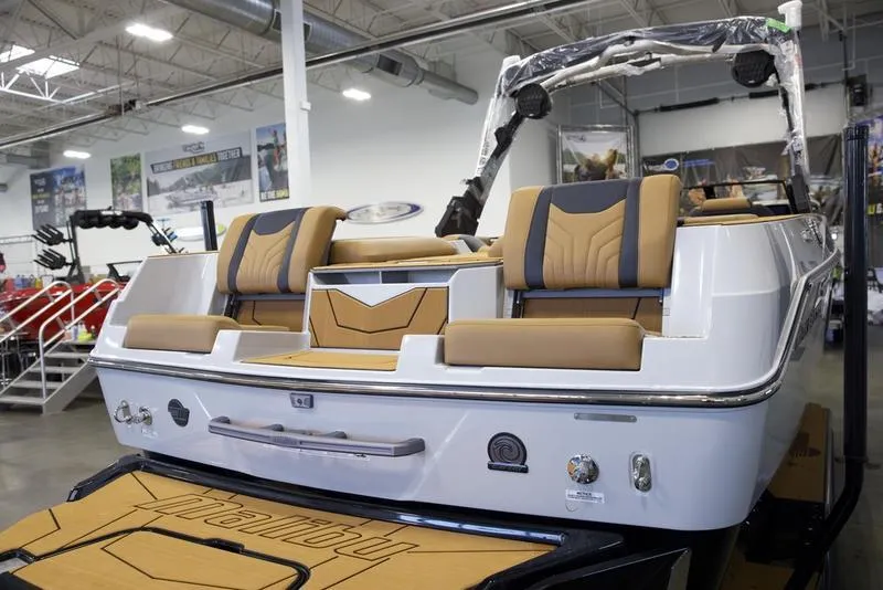 Slide: The Image of 2025 Malibu 25 LSV boat interior with tan and black seating in showroom. - 11