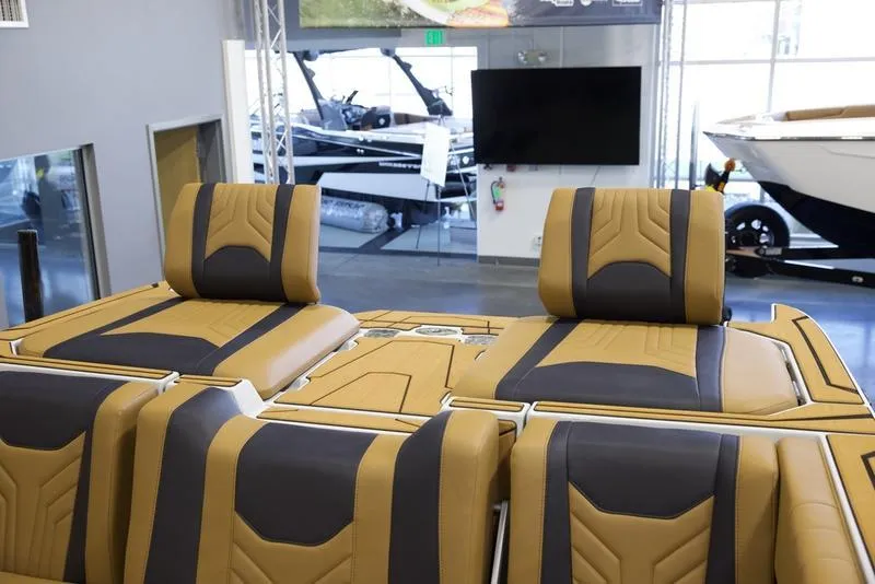 Slide: The Image of 2025 Malibu 25 LSV boat interior with tan and black seating in showroom. - 2